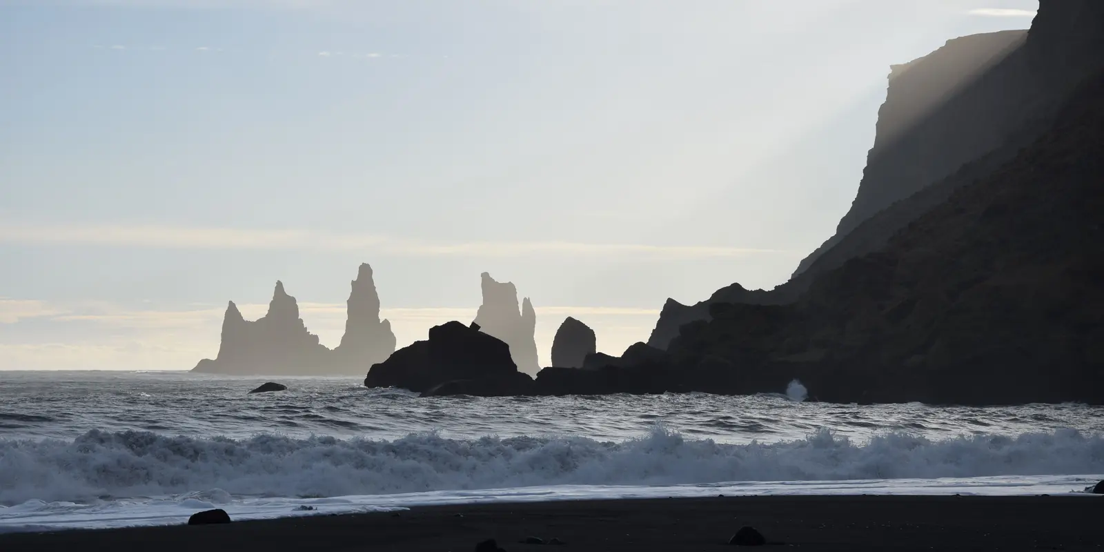 Playa de arena negra con roquedos en el mar